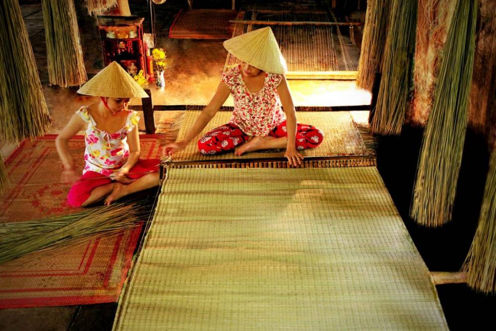 Una donna di Ben Tre sta tessendo delle stuoie.